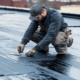 Professional roofer fixing a flat roof with visible cracks and damage.