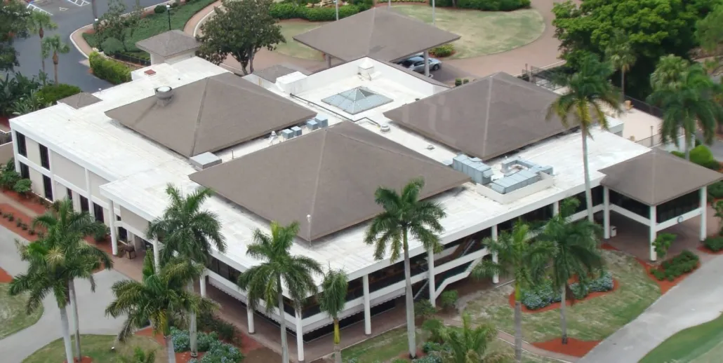 Aerial view of a two-storey commercial building combining white low-slope roof areas with brown hipped roof sections
