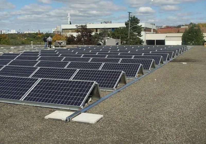 Low-tilt photovoltaic modules arranged on a gravel-surfaced flat roof
