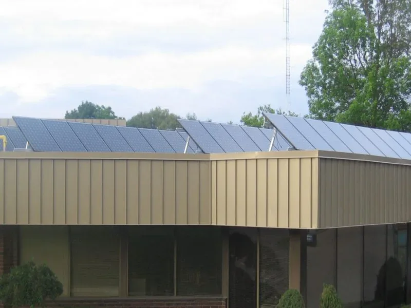 Roof-level view of photovoltaic modules mounted along a small commercial building