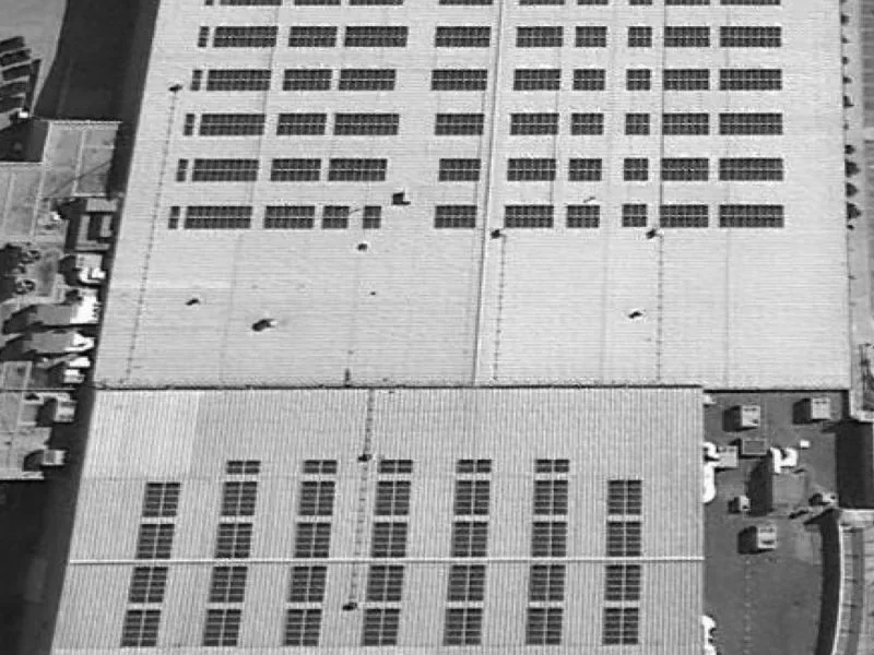 Overhead view of multiple photovoltaic arrays on a large institutional roof