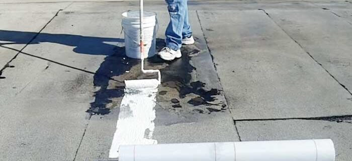 Roofing professional applying leveling compound to fix ponding water on a flat roof.