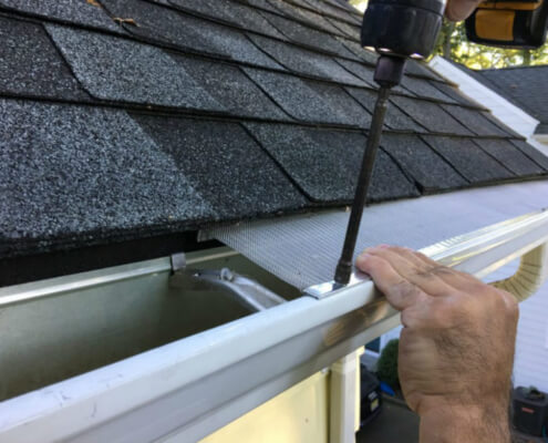 Close-up of aluminum eavestrough brackets and fasteners, emphasizing secure installation.